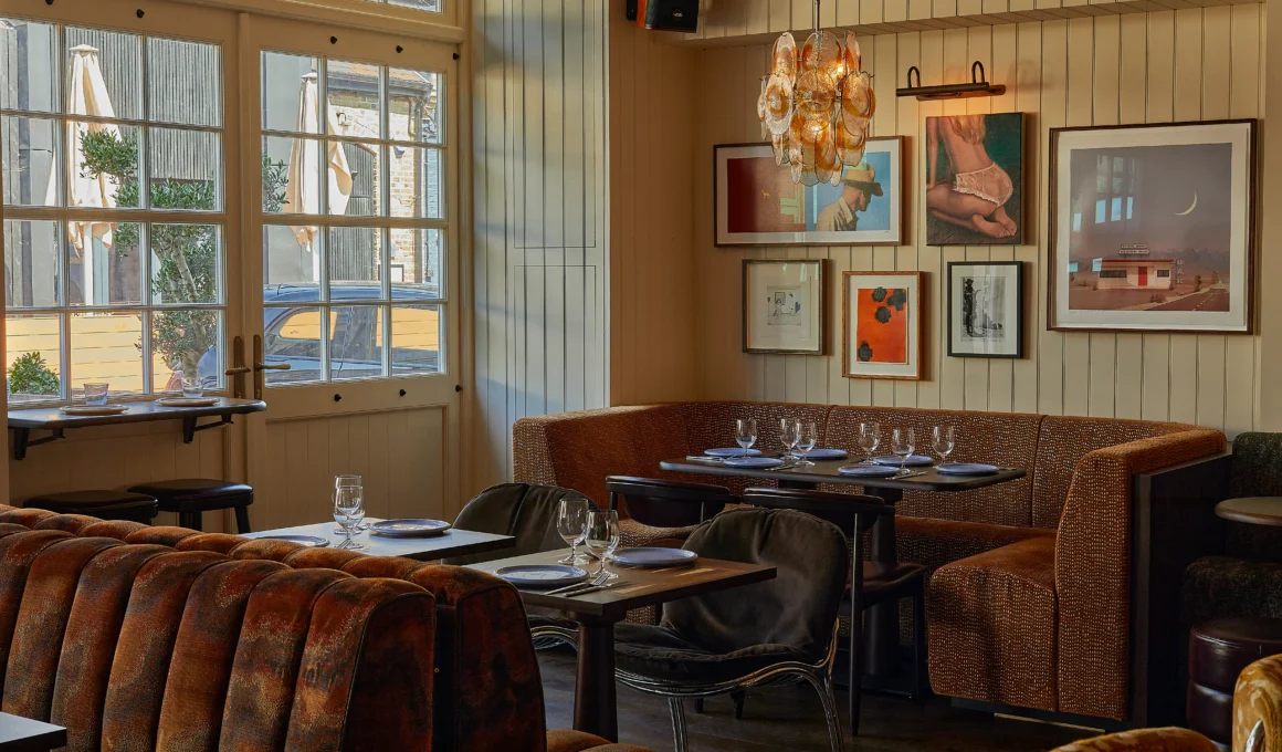 Bar Blondie by Macaulay Sinclair: dining room with paneled walls, gallery wall, amber glass chandelier, patterned banquettes and chrome chairs
