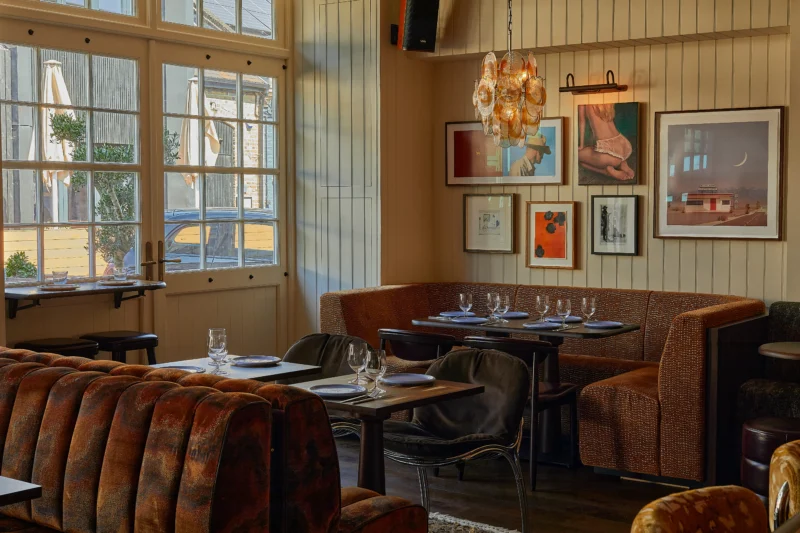 Bar Blondie by Macaulay Sinclair: dining room with paneled walls, gallery wall, amber glass chandelier, patterned banquettes and chrome chairs