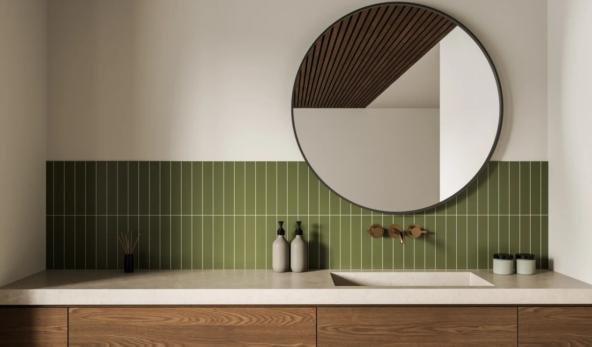 Modern bathroom with brass wall-mounted faucet, green vertical tile backsplash, round mirror and walnut wood vanity