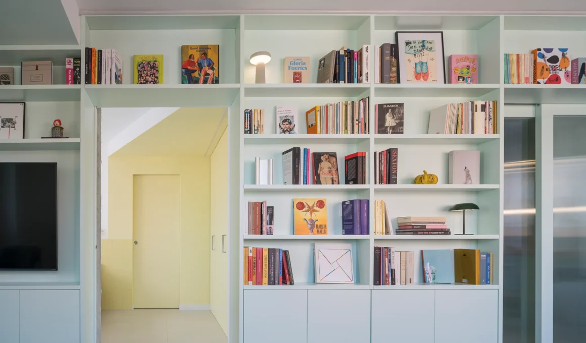 Casa POP by gon architects, opal-green lacquered bookcase with 27 shelves, TV wall, sliding mirror door to yellow bedroom