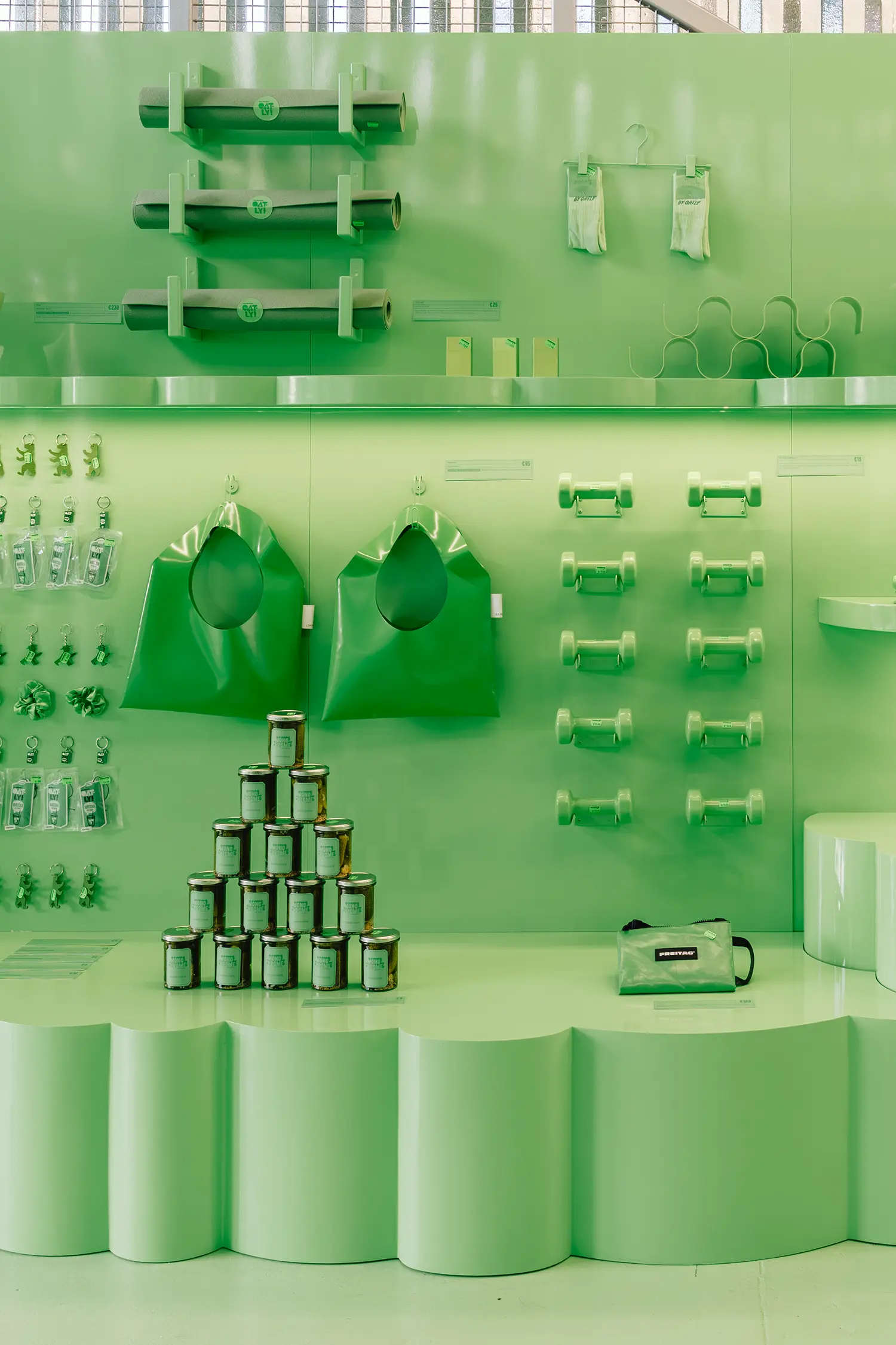 Green wall display with mats, dumbbells, bags and jars at Monochrome by Oatly by Cee Cee Creative. Photo: Aditya Christian, Mohit Amlani
