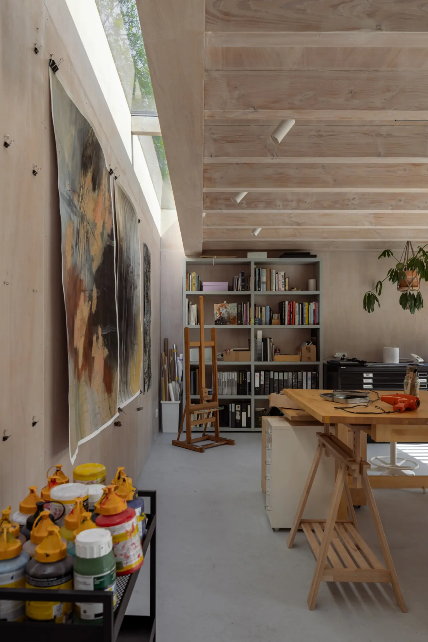Detail of the Rear House painter's studio, DP6 architectuurstudio: paintings pinned to the timber-lined wall beneath the skylight strip