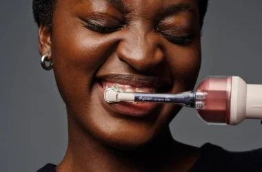 Dyson CameraJet electric toothbrush held in use, with camera and RFID sensor visible near the brush neck