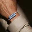 Luffu Link LTE health and safety band in brushed silver, worn on the wrist under a beige coat sleeve