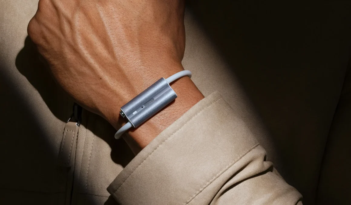 Luffu Link LTE health and safety band in brushed silver, worn on the wrist under a beige coat sleeve