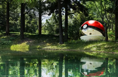 Poké Ball-Themed Hotel by NOT A HOTEL ARCHITECTS, red and white acrylic sphere with curved window beside a forest lake in Tomakomai, Hokkaido