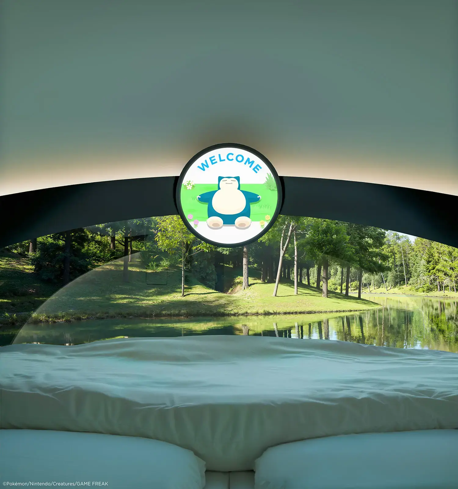 View from the circular bed of the Poké Ball-Themed Hotel by NOT A HOTEL ARCHITECTS, through the curved acrylic window to the lake