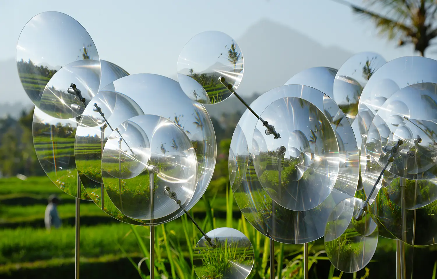 Eccentric Lenses by Vincent Leroy, clustered Fresnel lenses of varying diameters on thin poles above terraced rice fields in Munduk, Bali