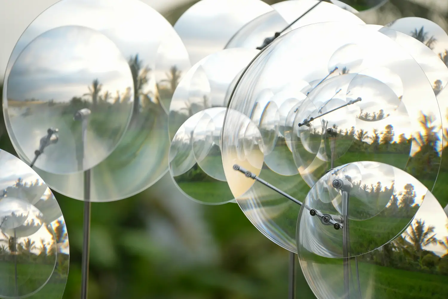 Eccentric Lenses by Vincent Leroy, close view of Fresnel lens discs and their off-centre pivot arms above rice fields in Munduk, Bali